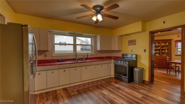 kitchen featuring stainless steel appliances, sink, hardwood / wood-style floors, white cabinetry, and tile counters