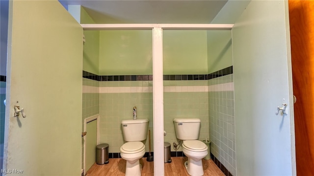 bathroom with wood-type flooring, toilet, and tile walls