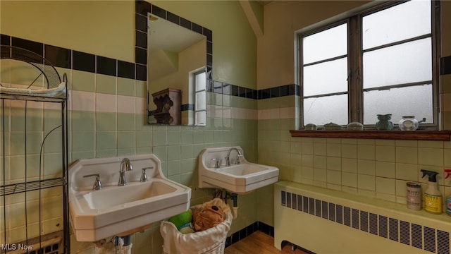 bathroom with wood-type flooring, radiator heating unit, and tile walls