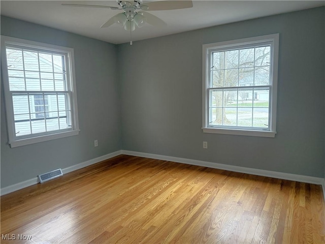 spare room with ceiling fan, light wood-type flooring, and a wealth of natural light