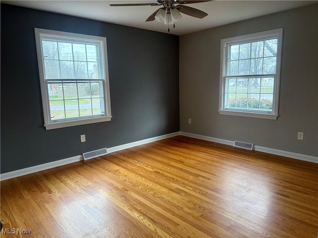 spare room with a wealth of natural light, ceiling fan, and light hardwood / wood-style floors