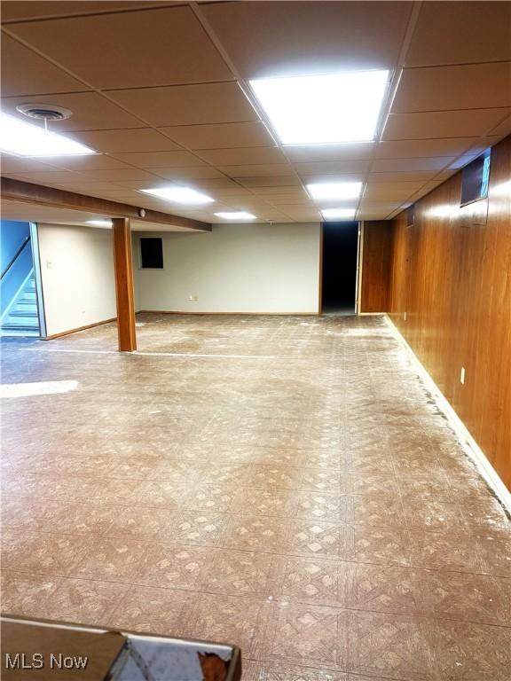 basement with wooden walls and a drop ceiling