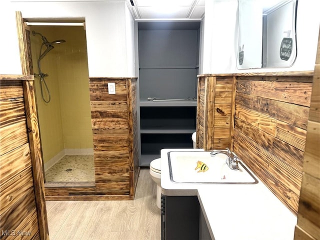 bathroom with hardwood / wood-style floors, vanity, toilet, and tiled shower