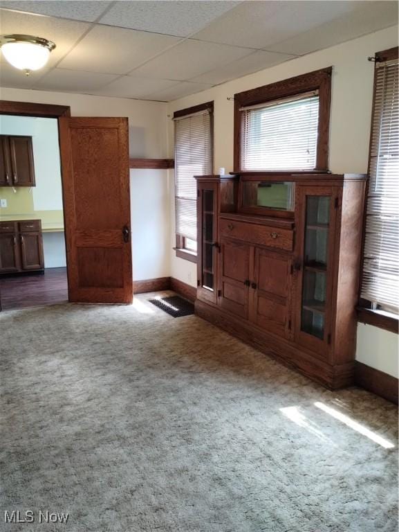 unfurnished living room featuring a drop ceiling and carpet floors