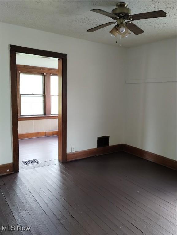 spare room with ceiling fan, dark hardwood / wood-style flooring, and a textured ceiling