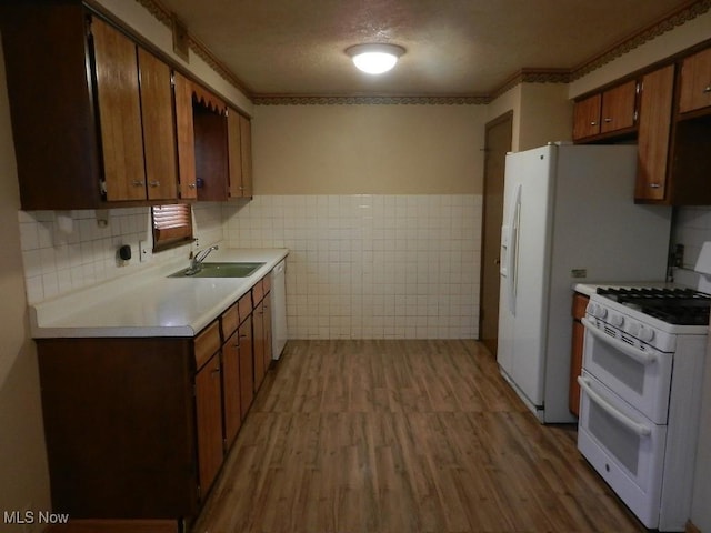 kitchen featuring white appliances, sink, ornamental molding, a textured ceiling, and light hardwood / wood-style floors