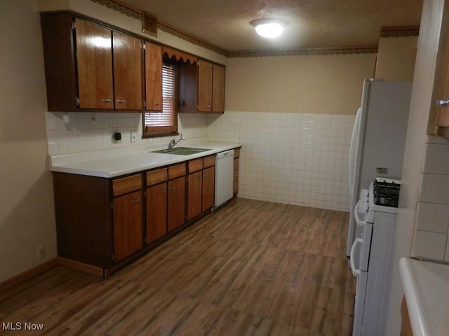 kitchen featuring sink, dark hardwood / wood-style floors, a textured ceiling, white appliances, and tile walls