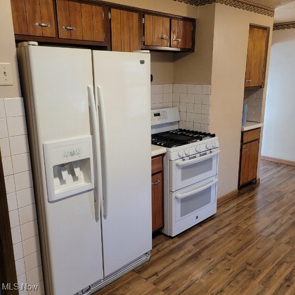 kitchen with white appliances, tasteful backsplash, and dark wood-type flooring