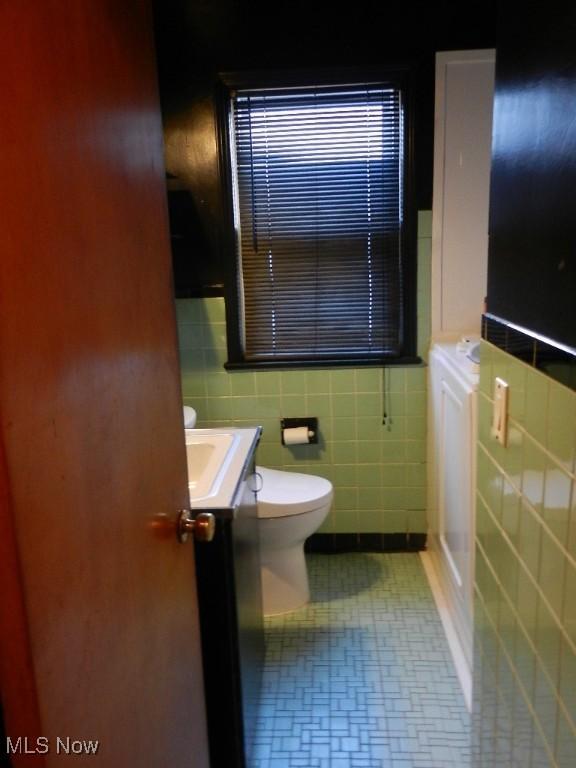 bathroom with vanity, toilet, and tile walls