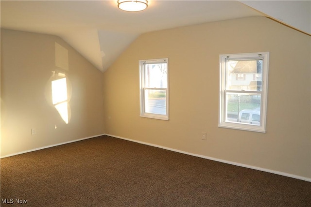 additional living space featuring dark carpet and vaulted ceiling