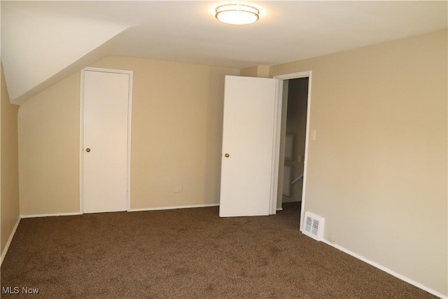 interior space with vaulted ceiling, dark carpet, and a closet