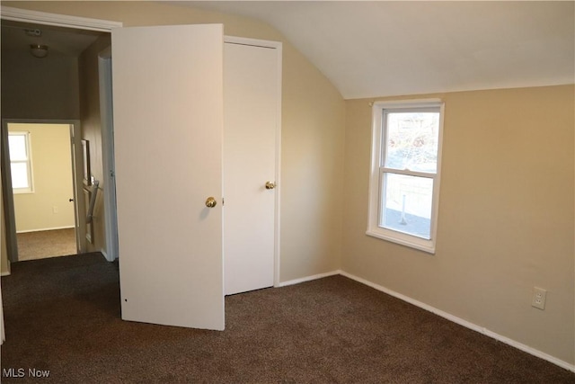 unfurnished bedroom featuring dark colored carpet and vaulted ceiling