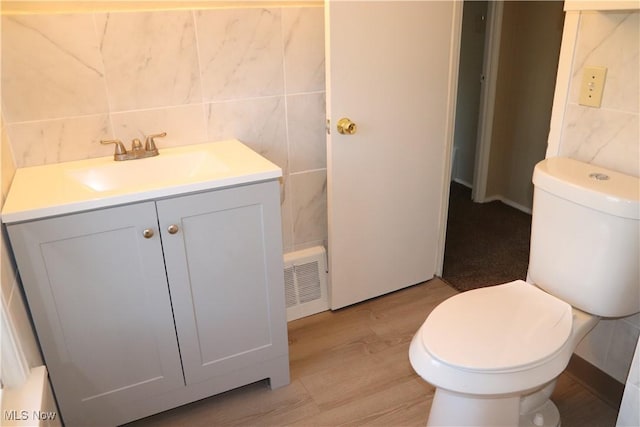 bathroom with hardwood / wood-style floors, vanity, toilet, and tile walls