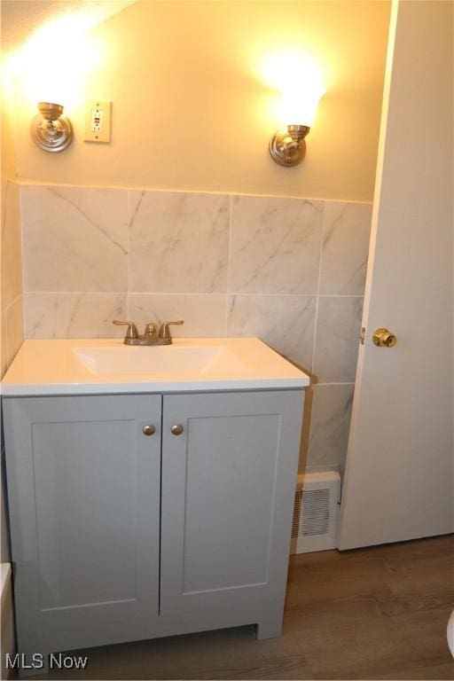 bathroom featuring vanity, wood-type flooring, and tile walls