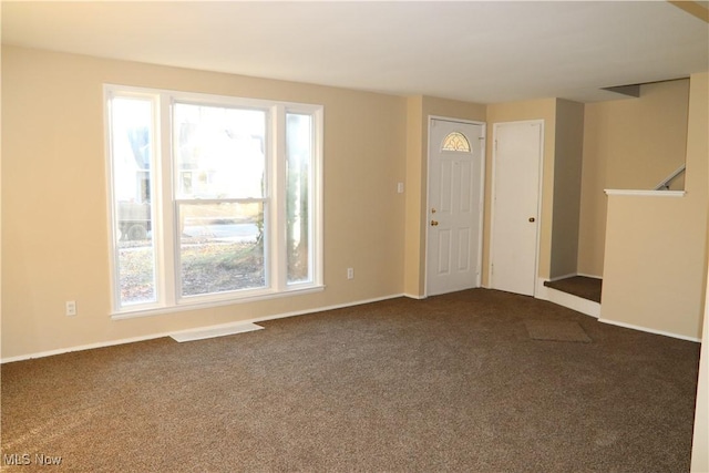 empty room with a healthy amount of sunlight and dark carpet