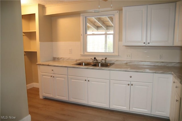 kitchen featuring wood-type flooring, white cabinetry, and sink