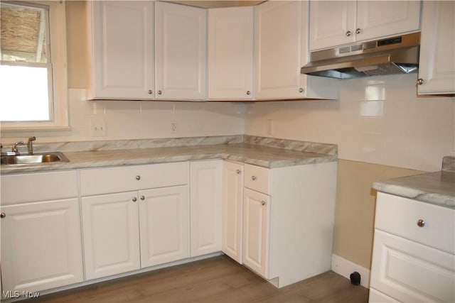 kitchen featuring hardwood / wood-style flooring, white cabinets, sink, and tasteful backsplash