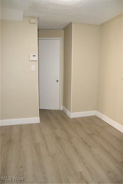 unfurnished room featuring a textured ceiling and light wood-type flooring