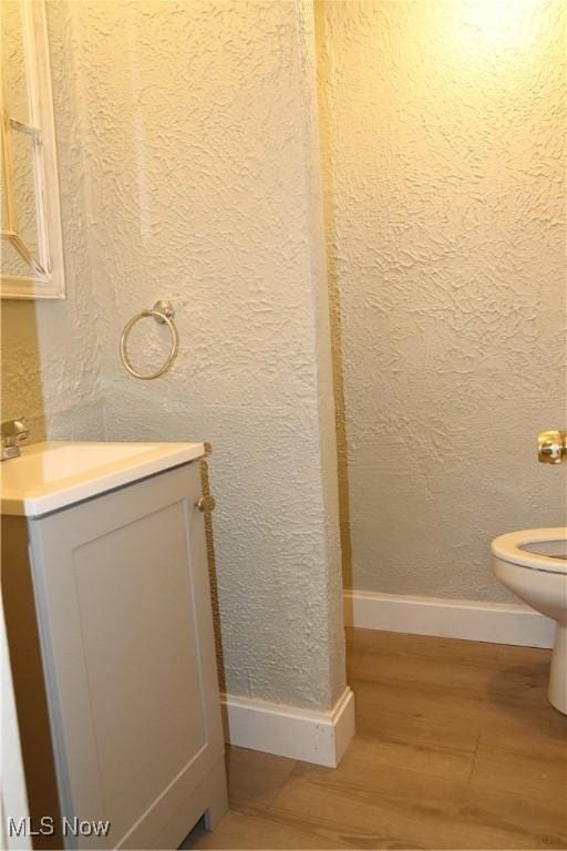 bathroom with hardwood / wood-style floors, vanity, and toilet