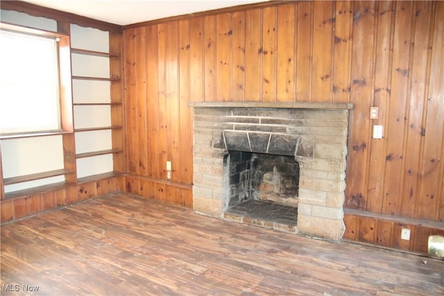 living room featuring dark hardwood / wood-style floors, wood walls, and a stone fireplace