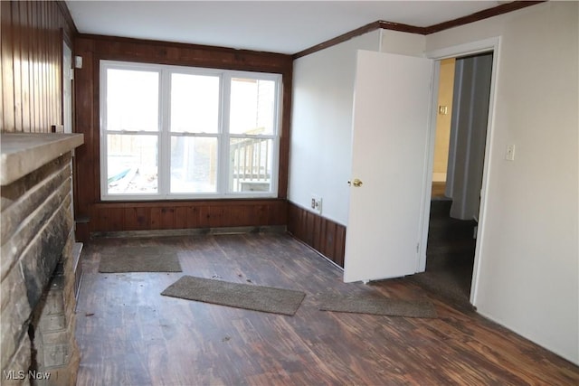 spare room with a fireplace, crown molding, and dark wood-type flooring