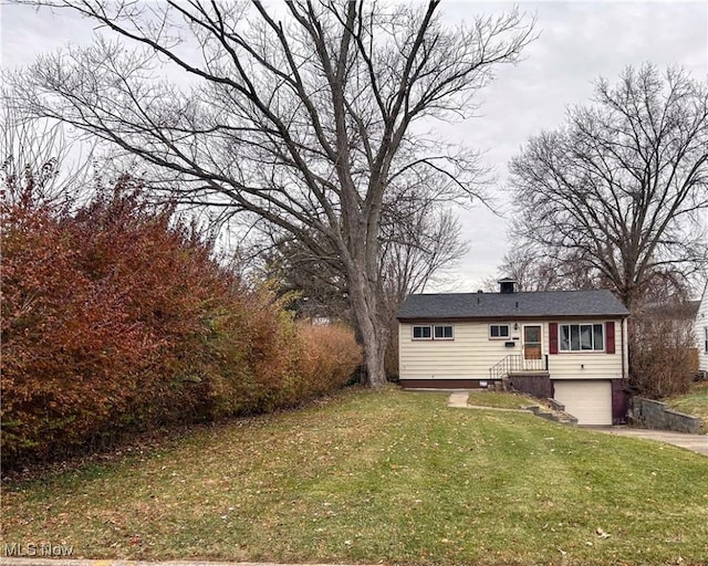 rear view of house featuring a lawn and a garage