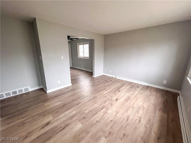 spare room featuring ceiling fan, a baseboard radiator, and hardwood / wood-style flooring