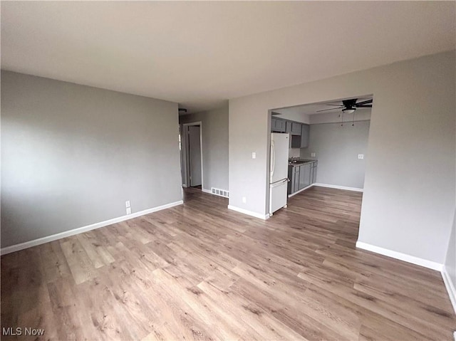 unfurnished living room featuring ceiling fan and light wood-type flooring