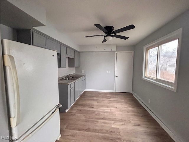 kitchen with white fridge, gray cabinets, light hardwood / wood-style floors, and sink