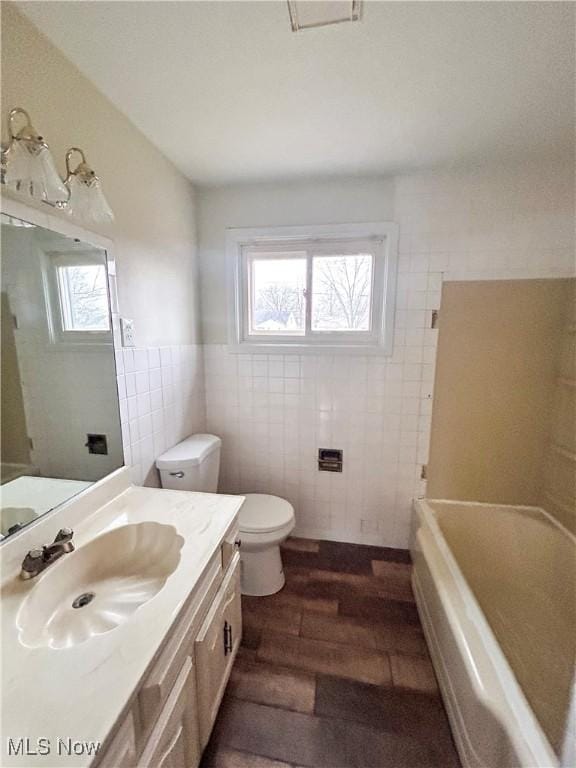 bathroom featuring hardwood / wood-style flooring, vanity, tile walls, and a wealth of natural light