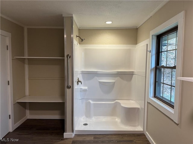 bathroom featuring a textured ceiling, a shower, wood-type flooring, and ornamental molding