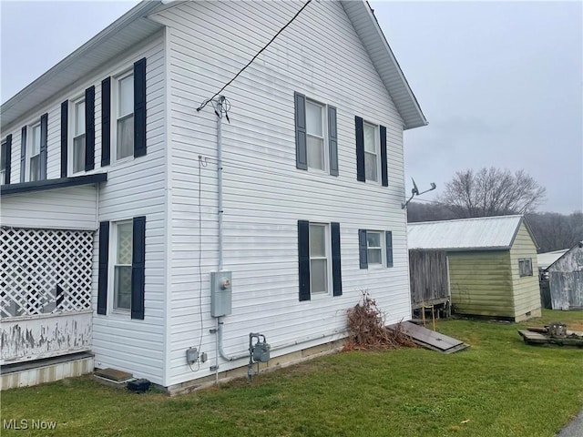 view of side of home featuring a shed and a lawn