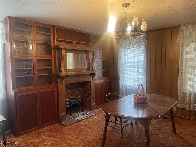 carpeted dining area with a wood stove, wood walls, and an inviting chandelier