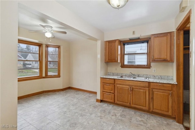 kitchen featuring light stone countertops, sink, and ceiling fan