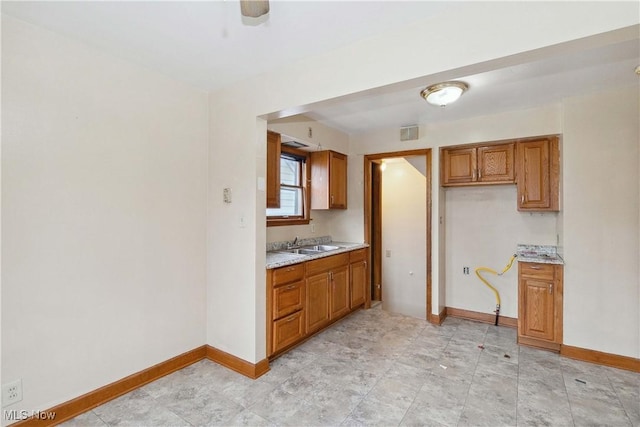 kitchen featuring light stone countertops and sink