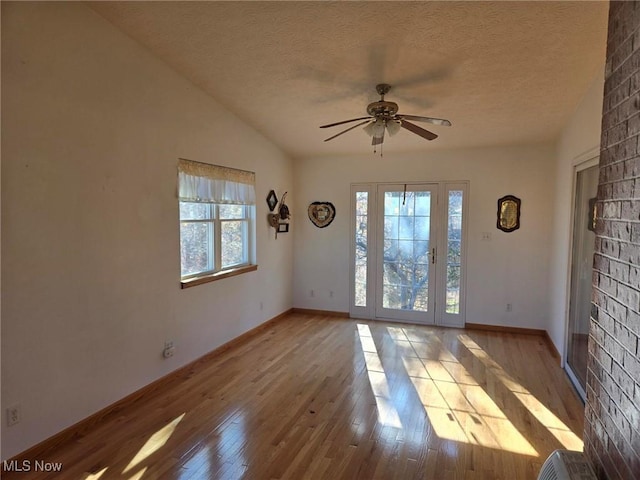 empty room with ceiling fan, lofted ceiling, light hardwood / wood-style flooring, and a textured ceiling