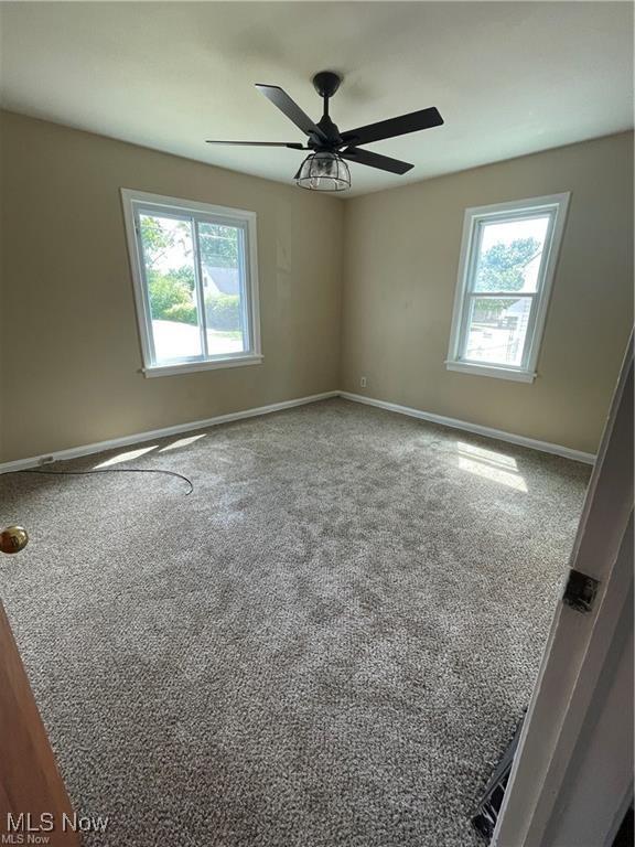 spare room with carpet flooring, a wealth of natural light, and ceiling fan