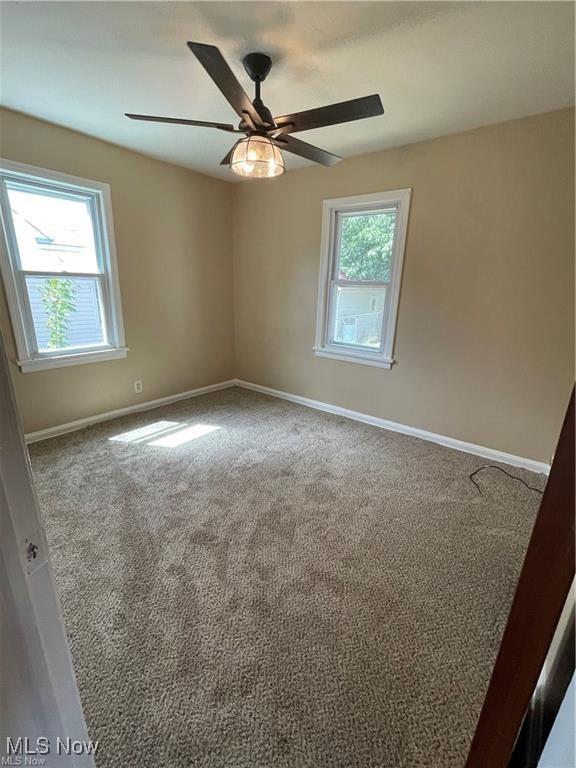 carpeted empty room with a wealth of natural light and ceiling fan