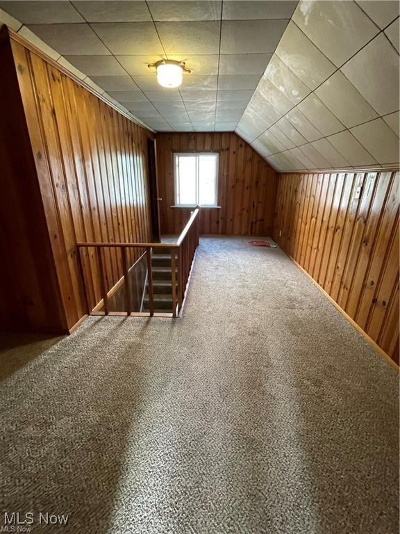 additional living space with carpet floors and wood walls