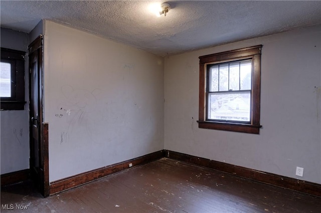 empty room with a textured ceiling and dark hardwood / wood-style floors