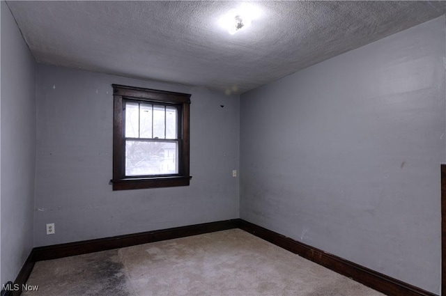 carpeted empty room featuring a textured ceiling