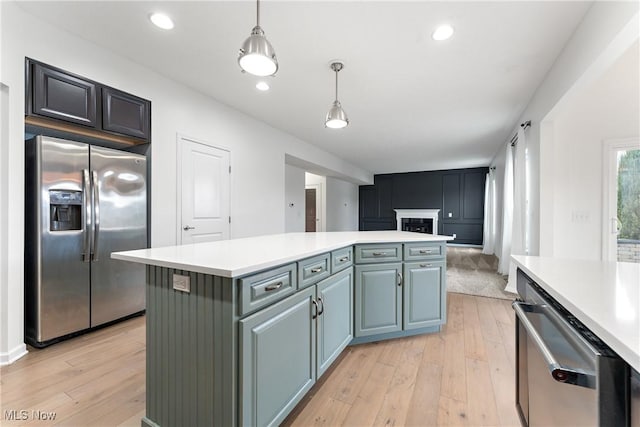 kitchen featuring a kitchen island, light hardwood / wood-style floors, stainless steel appliances, and hanging light fixtures