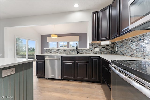 kitchen with pendant lighting, backsplash, sink, light hardwood / wood-style flooring, and stainless steel appliances