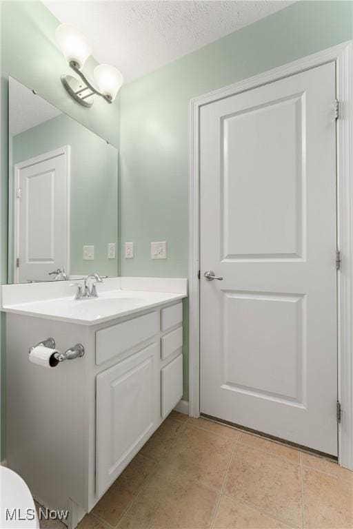 bathroom with tile patterned flooring, vanity, and a textured ceiling