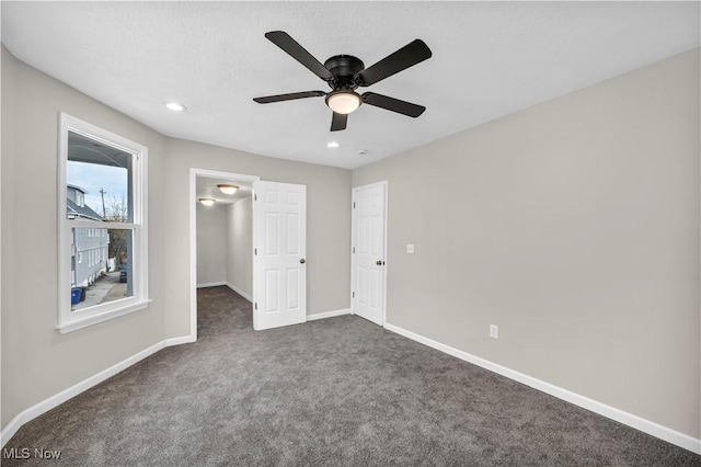 unfurnished bedroom featuring dark colored carpet and ceiling fan