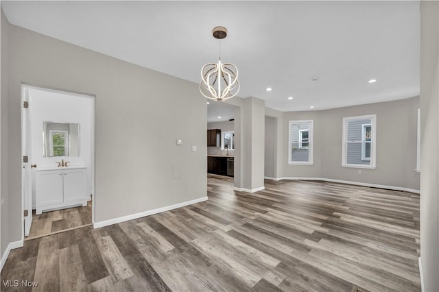 unfurnished living room featuring sink, hardwood / wood-style floors, and a notable chandelier