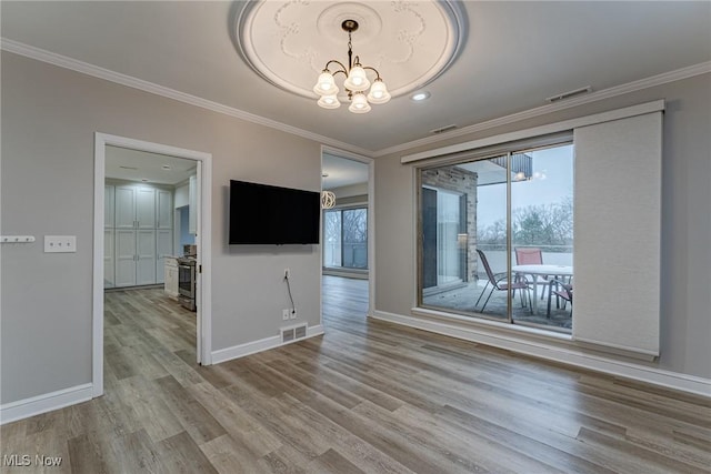 empty room with hardwood / wood-style floors, a chandelier, and ornamental molding