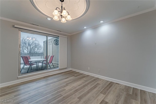 unfurnished dining area featuring ornamental molding, light wood-type flooring, and a notable chandelier