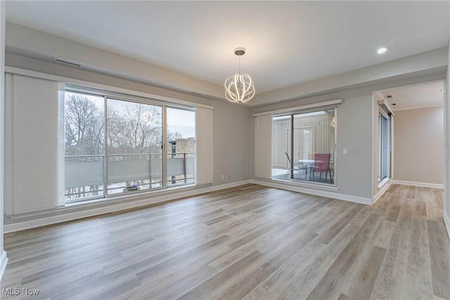 unfurnished room with a notable chandelier and light wood-type flooring