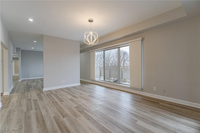 empty room with a notable chandelier and light wood-type flooring